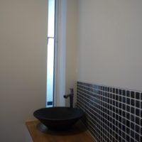 1階のトイレはブルーのタイルと黒い手洗いでシックに。