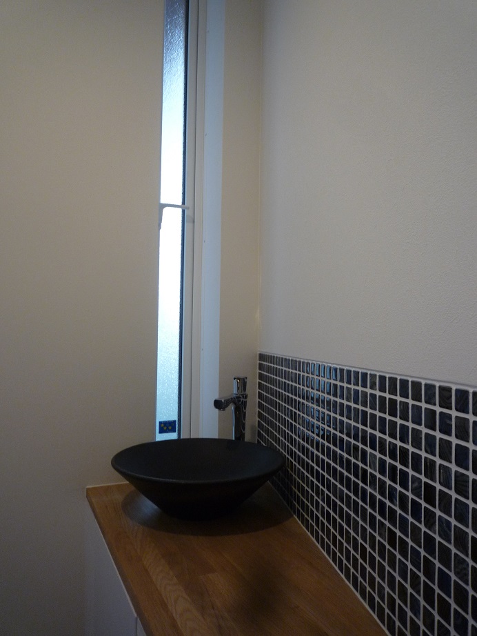 1階のトイレはブルーのタイルと黒い手洗いでシックに。